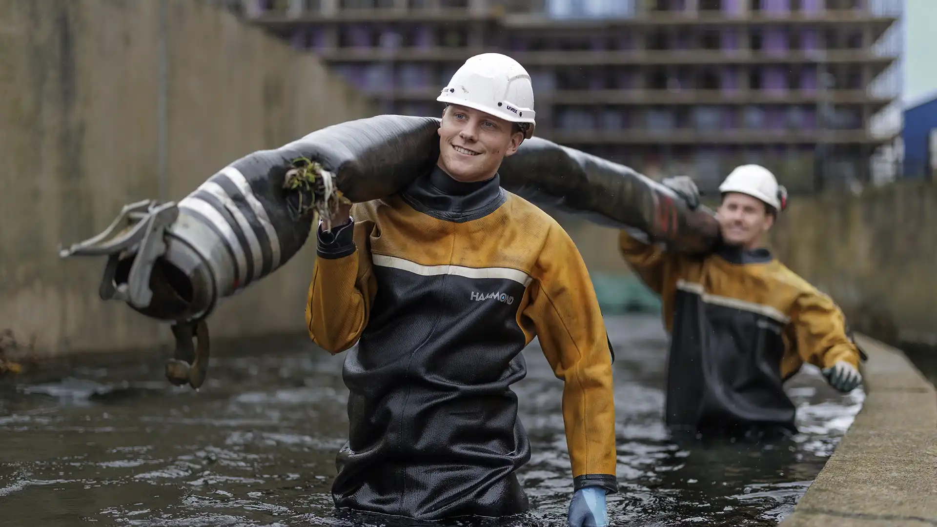 Specialist team carrying equipment through a water channel during in-water operations and confined space work