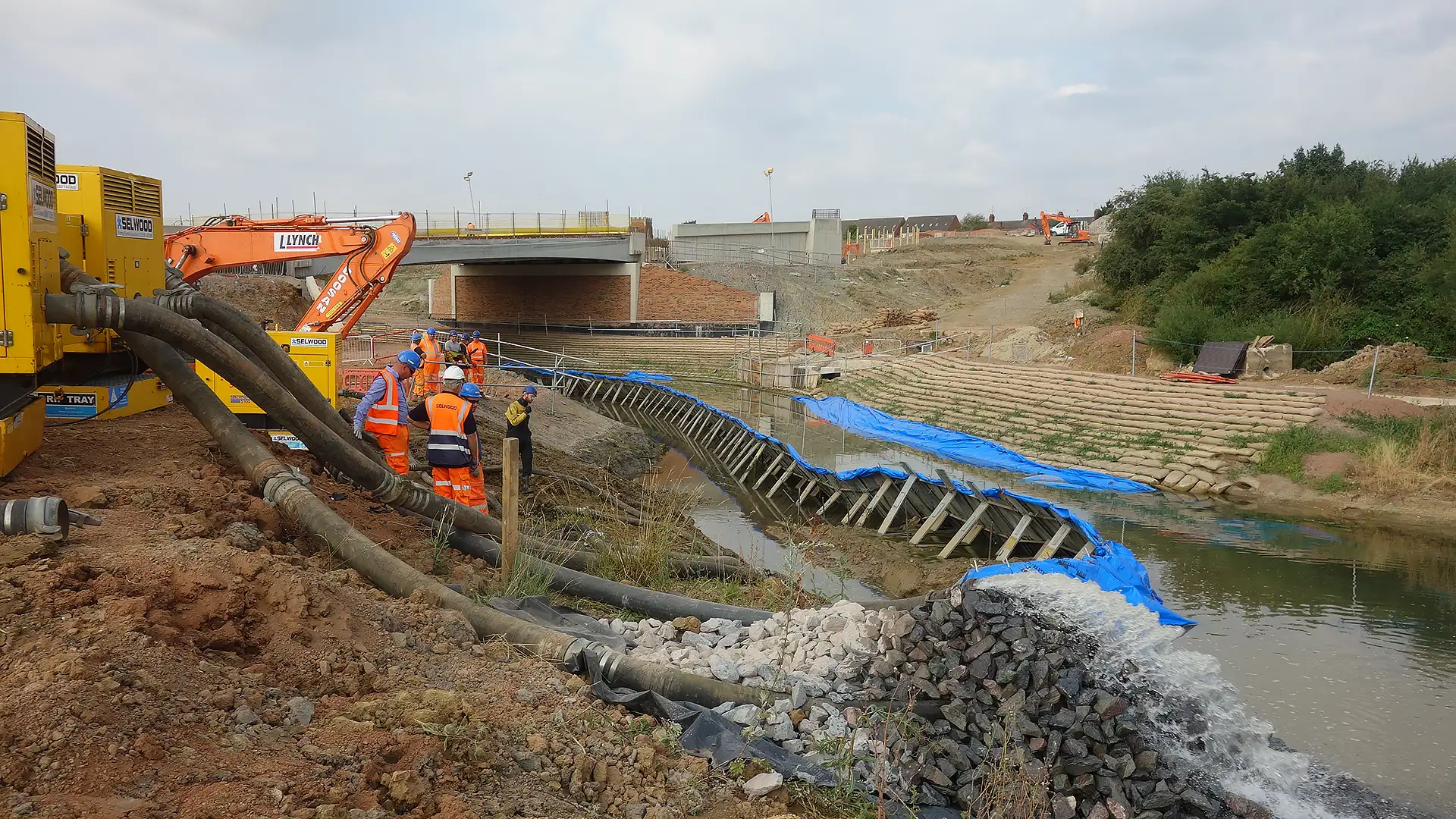 Temporary frame dam installed beneath a bridge to create a dry working area for infrastructure and highway construction.