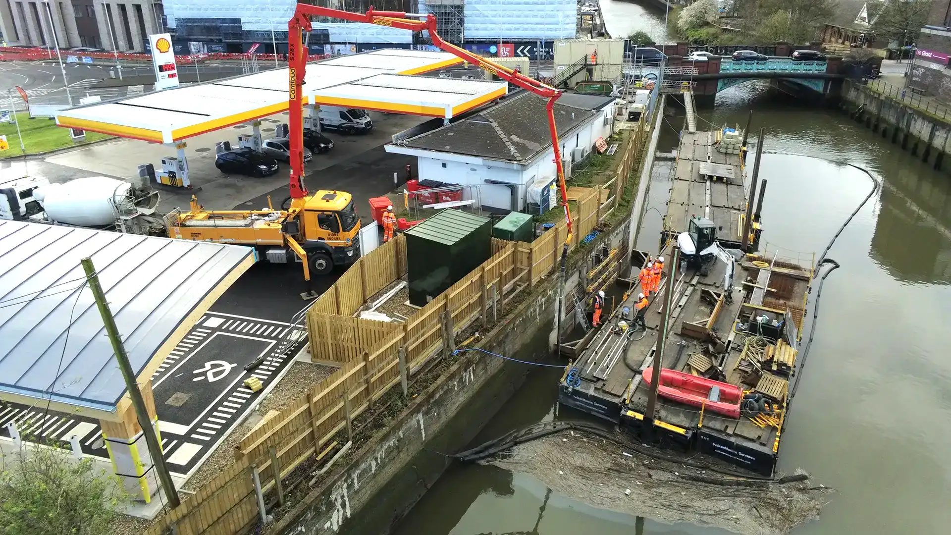 Construction team working from floating platforms alongside a canal retaining wall