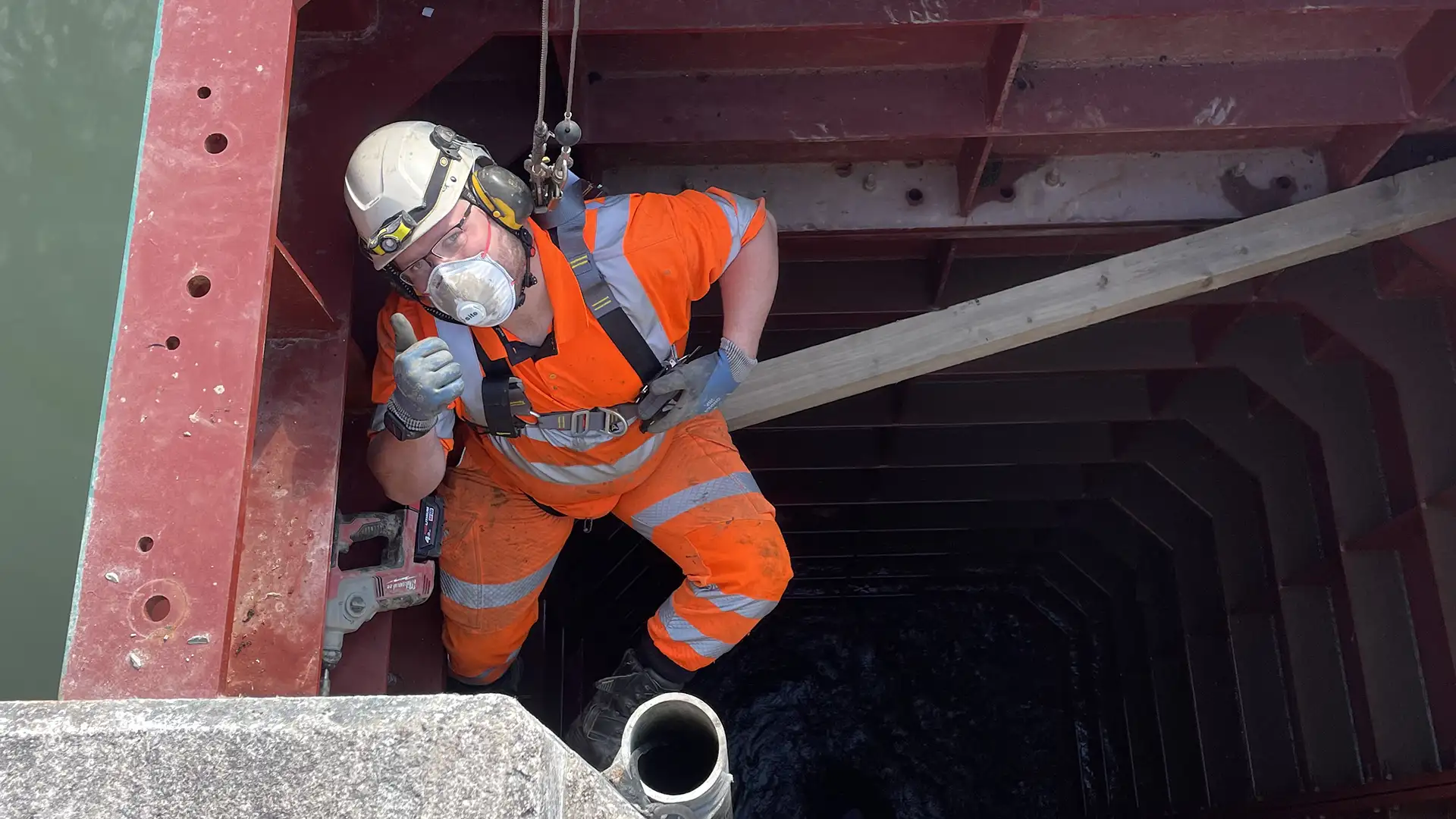 Engineer working inside a temporary marine enclosure using confined space access equipment and full safety PPE.