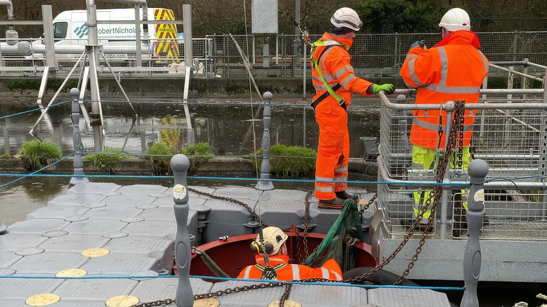 Confined space team preparing safe access to a below-water structure from a floating work platform.