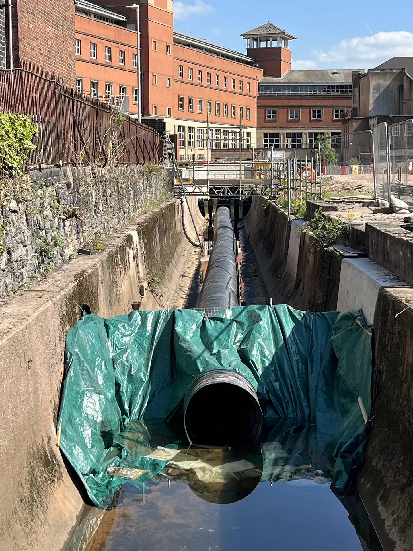 Large diameter temporary flow diversion pipeline installed within a concrete channel to maintain water flow during civil engineering works.