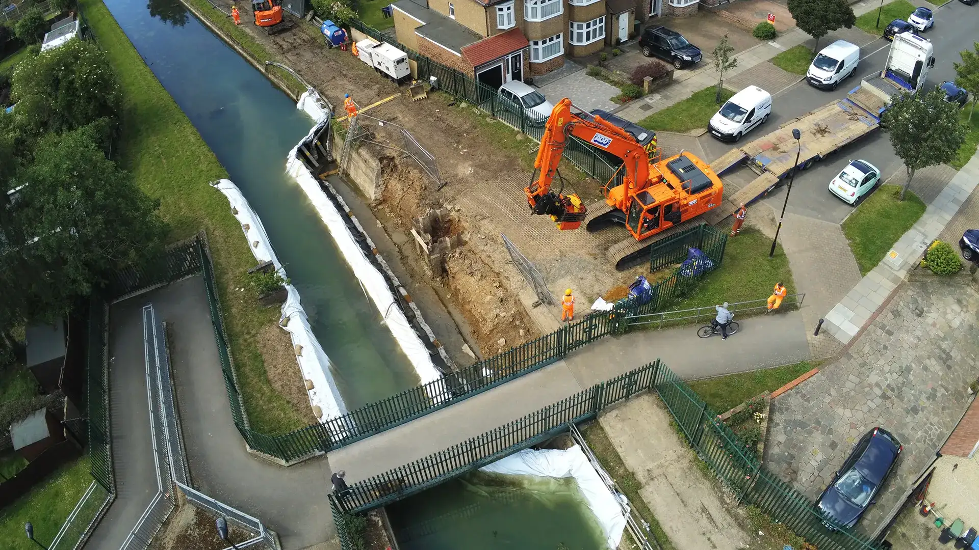 Aerial view of a frame dam system creating a dry working area beside an urban waterway