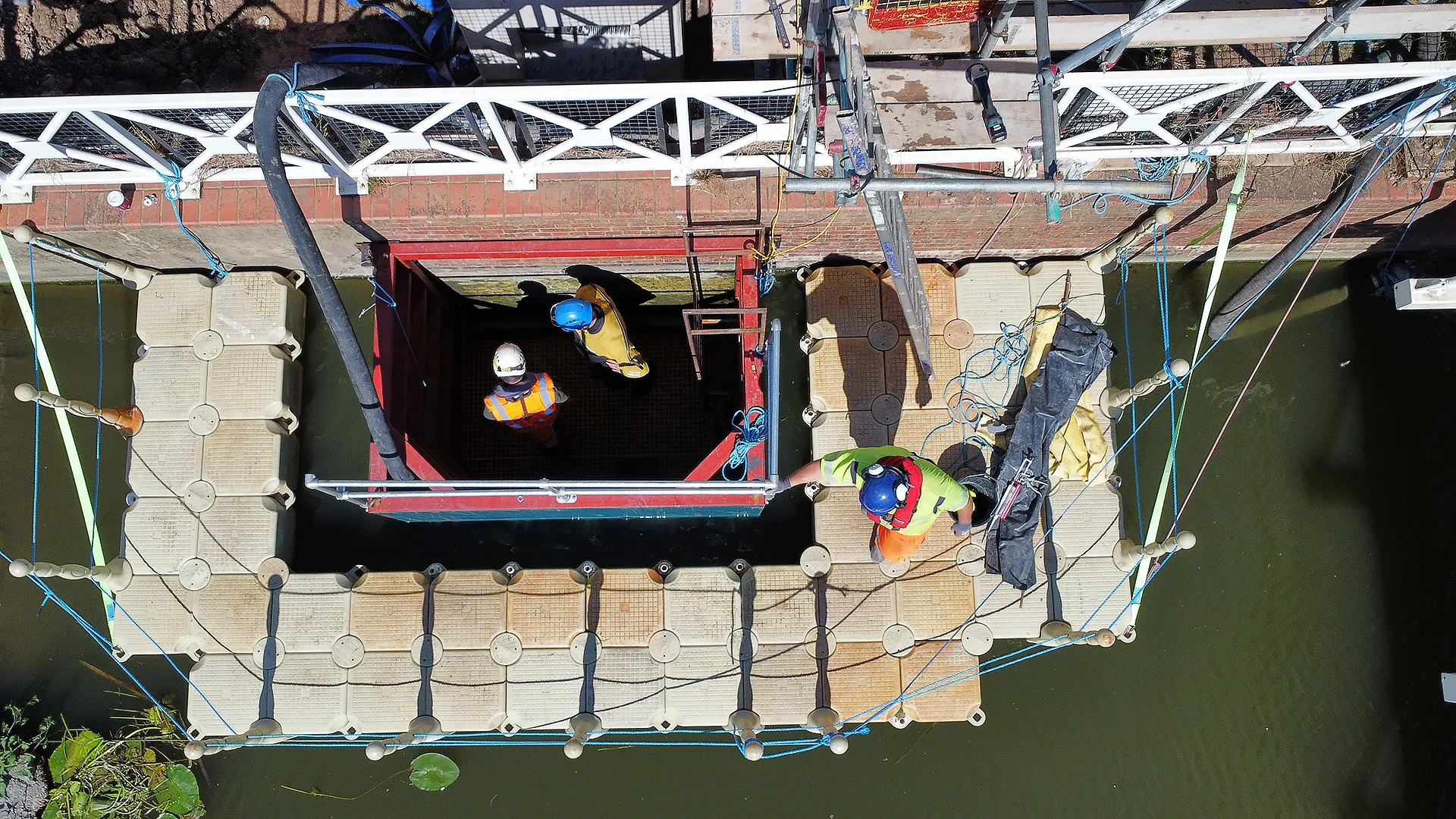 Overhead view of operatives working inside a dewatered limpet dam surrounded by floating pontoons