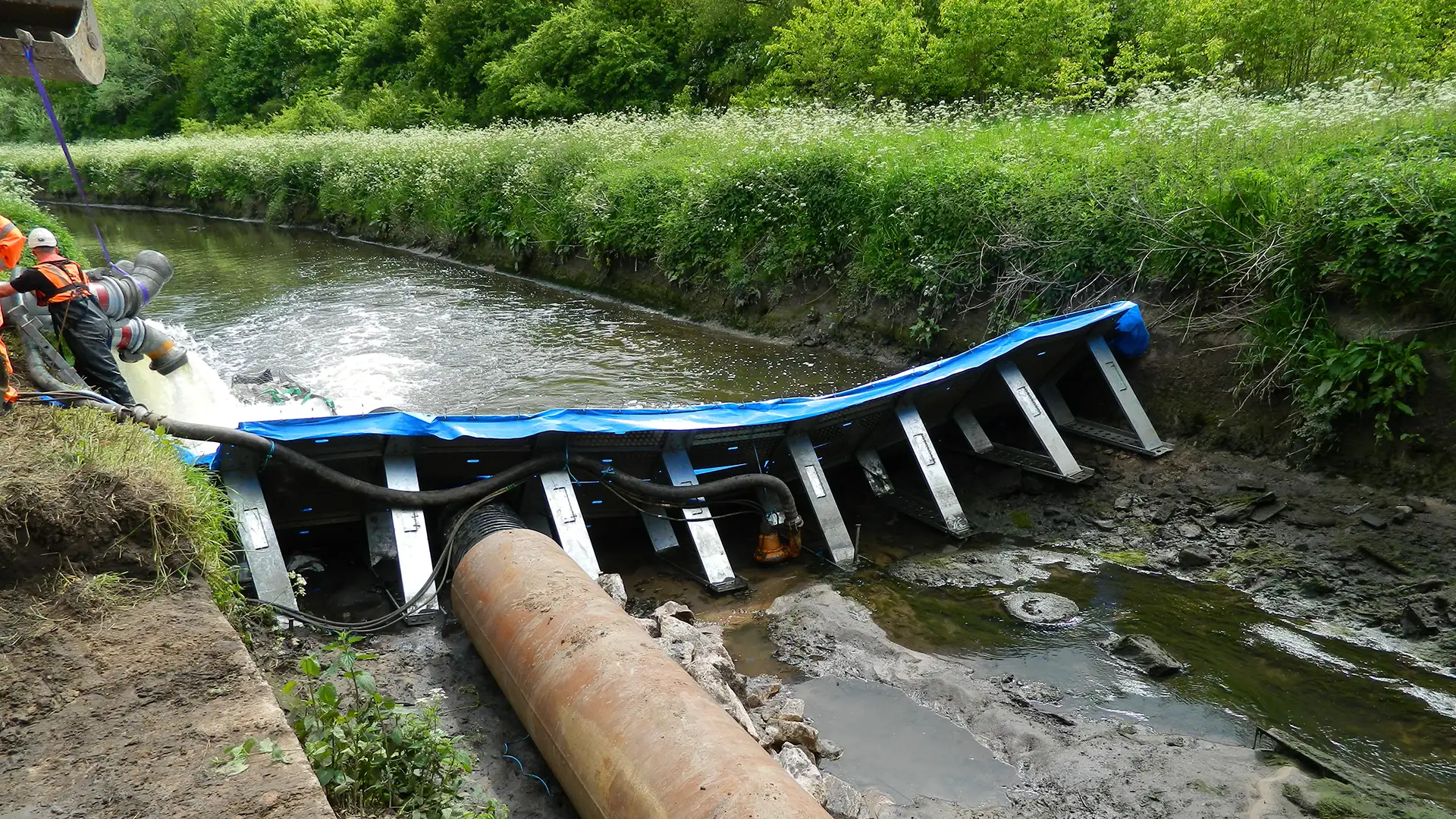 Temporary frame dam with pumped flow diversion maintaining river flow during civil engineering works.
