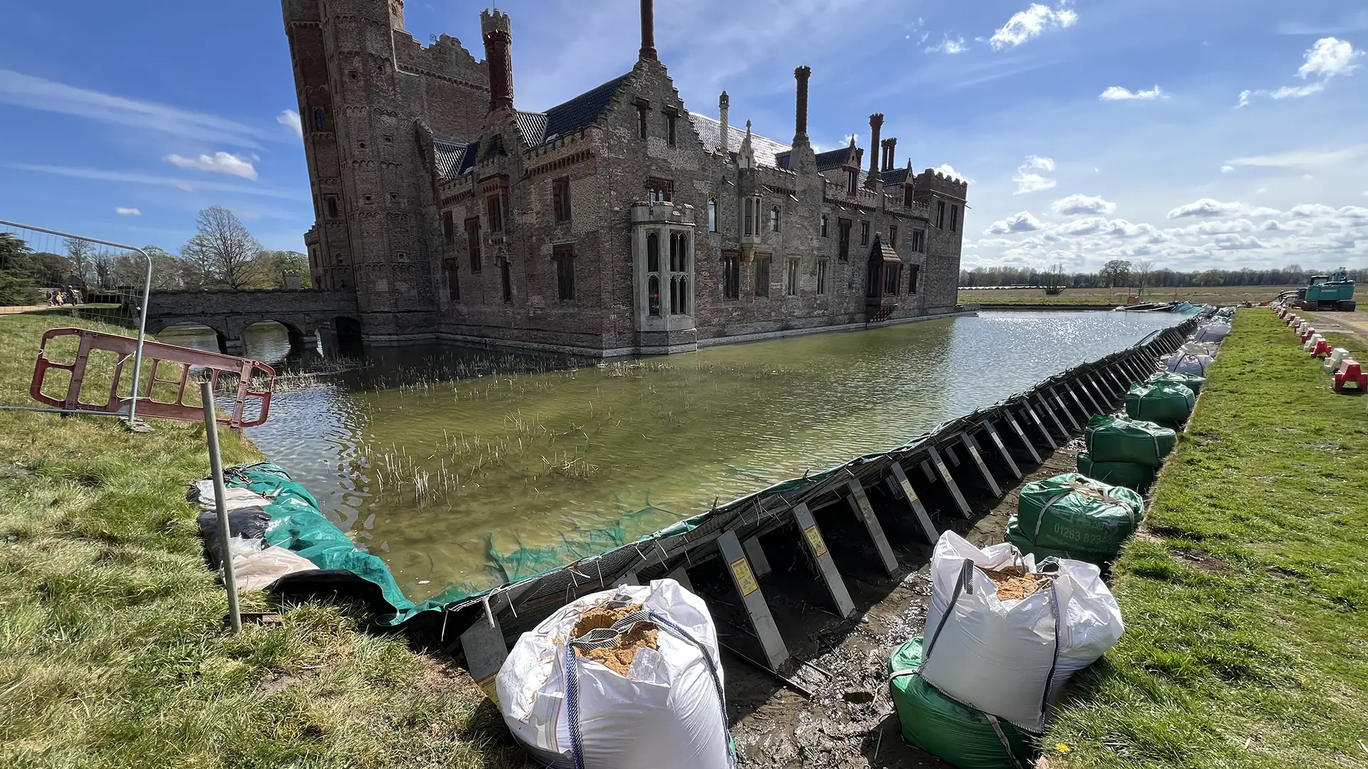 Temporary frame dam retaining water around a historic building during construction and conservation works.