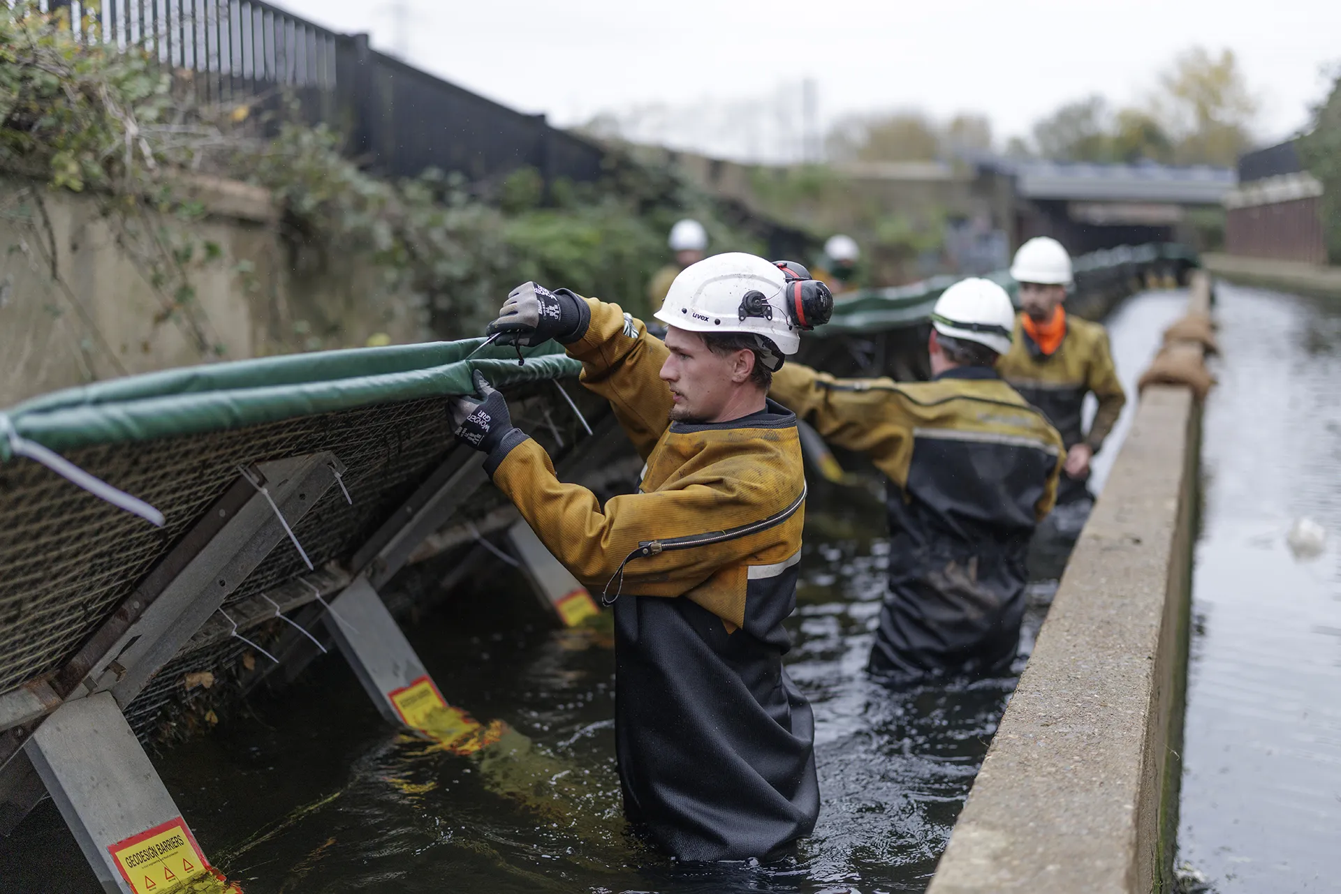 High Water specialists working alongside a temporary water control barrier within a live canal.