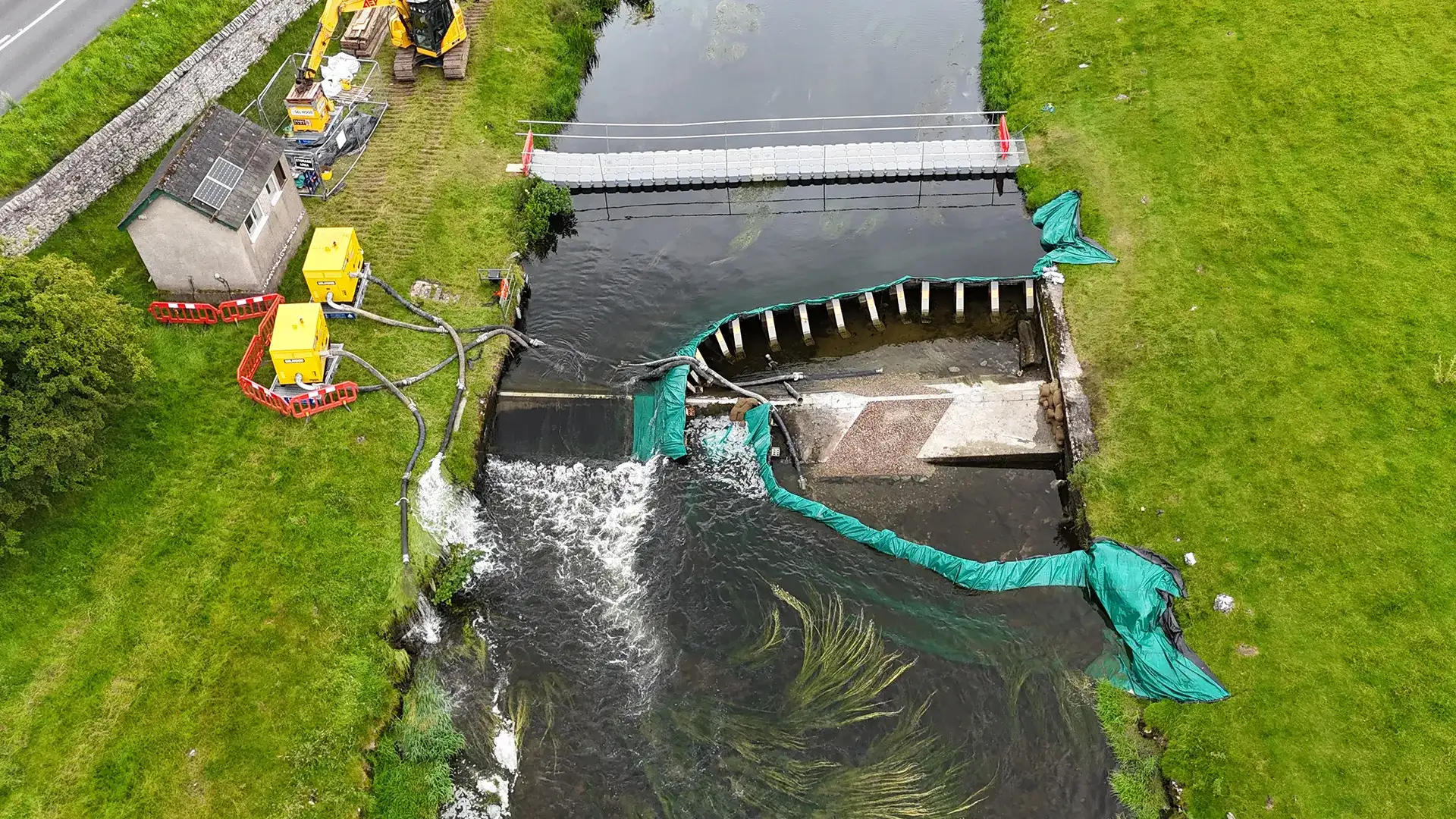 Aerial view of temporary water control and pumping equipment around river weir works