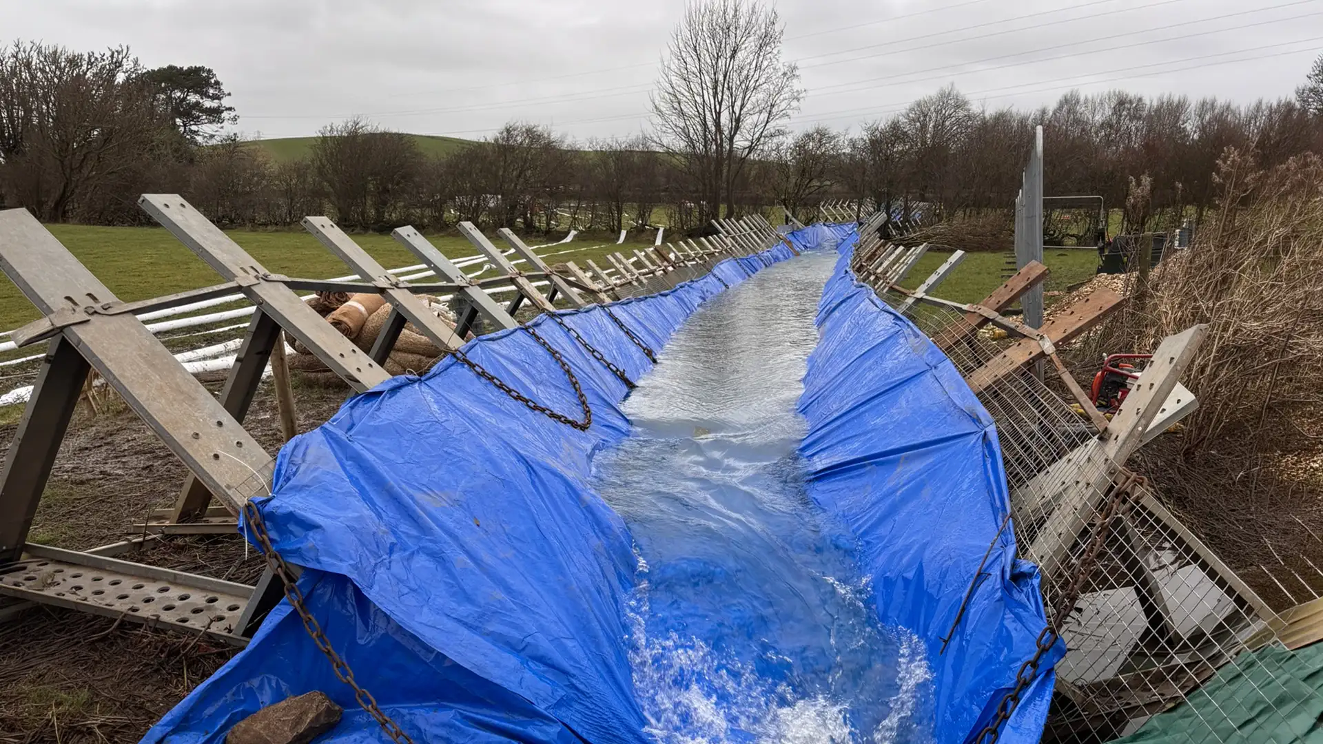 Temporary lined water diversion channel carrying controlled water flow through a flood response site