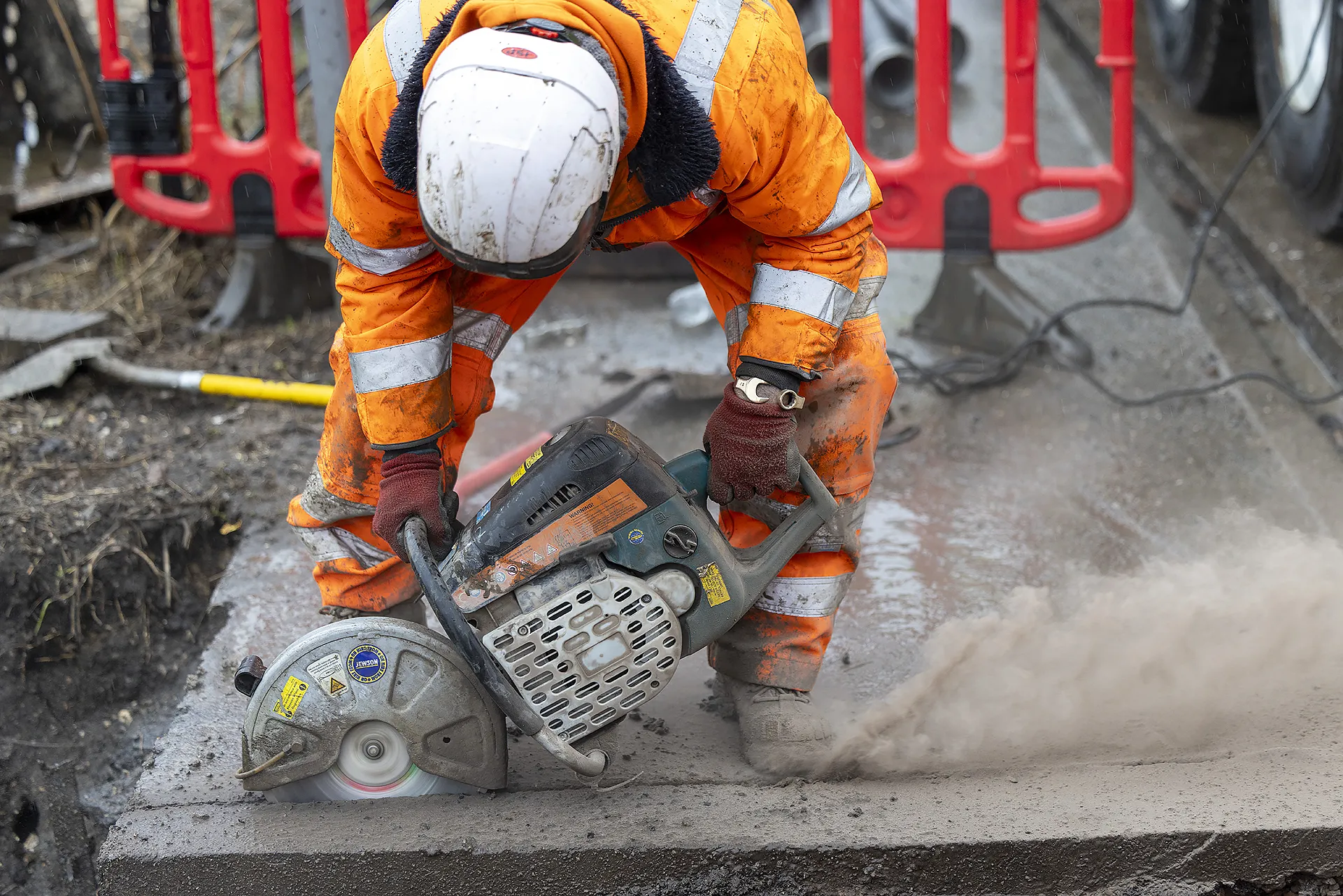 Site engineer cutting concrete during preparation for a temporary water engineering installation.