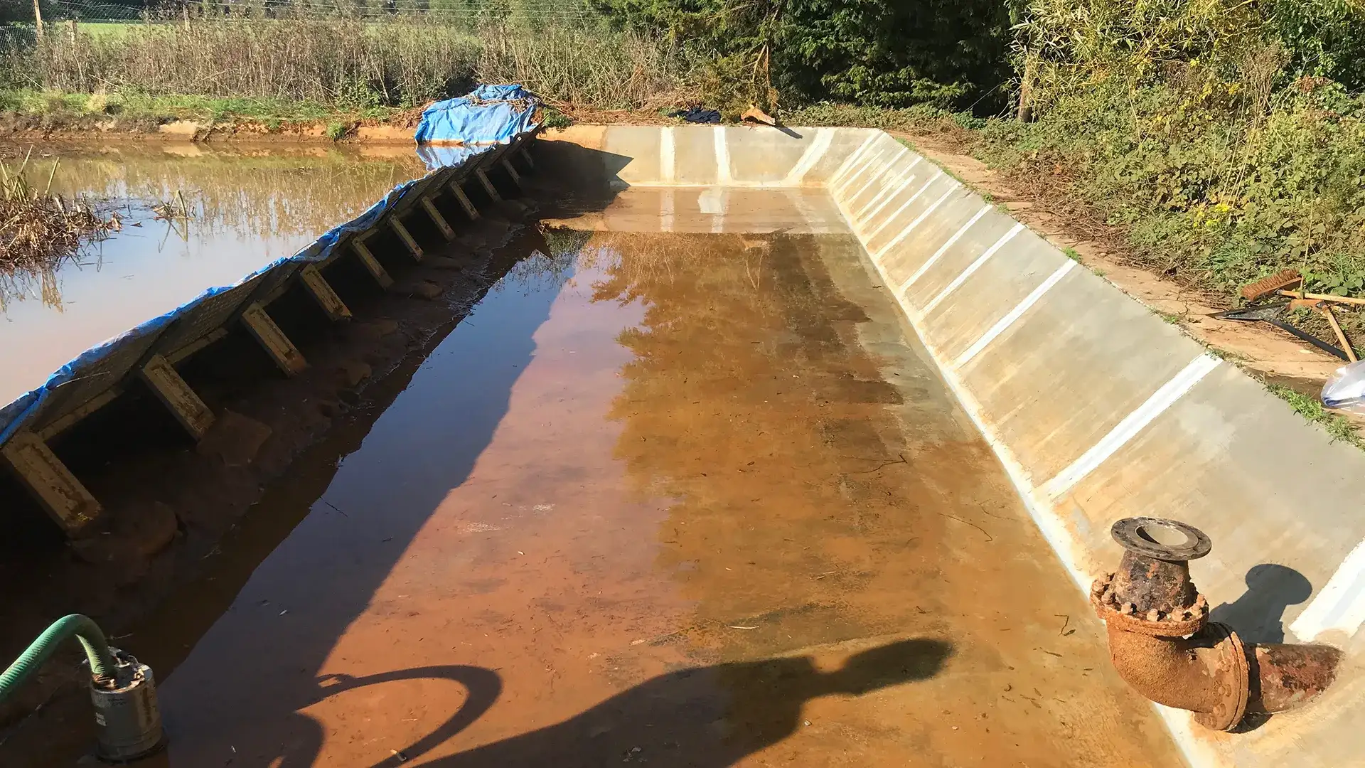 Partially drained treatment lagoon with temporary retaining works and exposed pipework