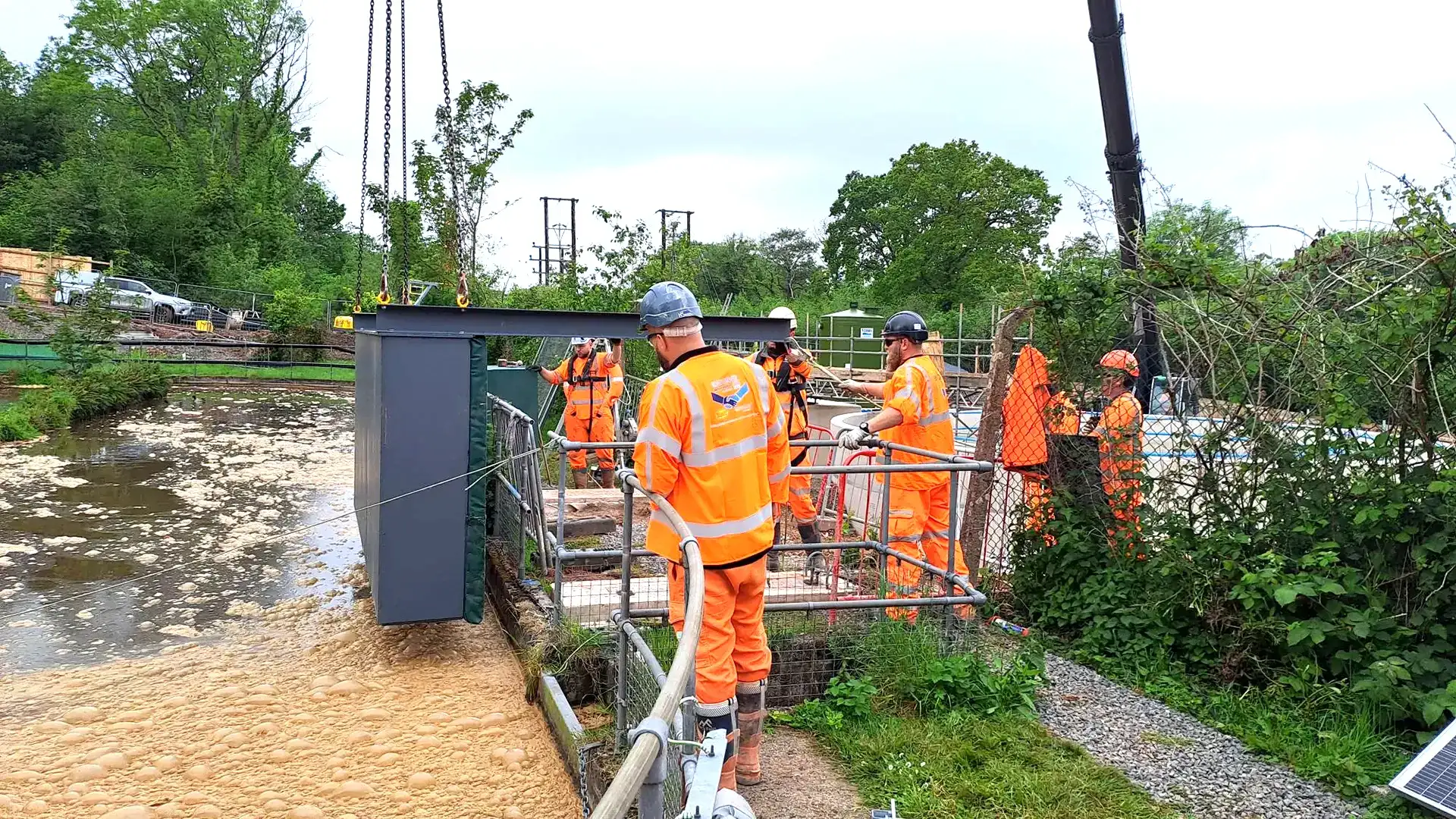 Operatives guiding a temporary water control barrier into position at a water treatment site